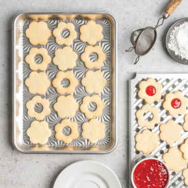 overhead of novelty shape cookies on starburst quarter sheet pan; multi task cooling rack with jam nearby