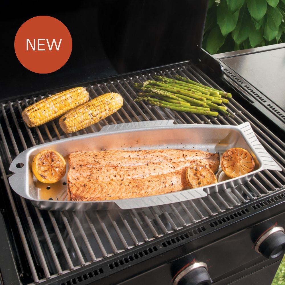 Image of new fish and seafood griller on the grill filled with cooked salmon and lemons, asperagus and corn.