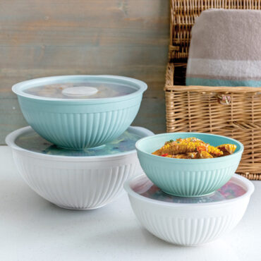 8 piece covered bowl set staged on countertop with one bowl uncovered holding corn cobs