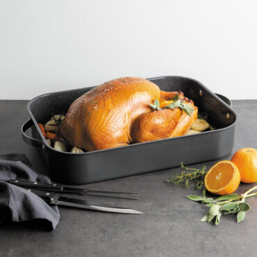 cooked turkey and veggies staged inside Nordic Ware Verde Grand Roaster with speckled nonstick interior and stainless steel handles