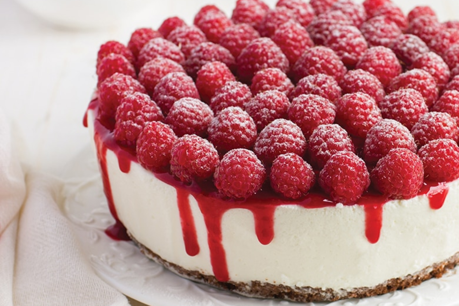 Cheesecake topped with raspberries and raspberry sauce.