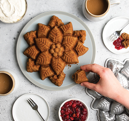 Image of baked spiced cake in new Nordic Ware Poinsettia cake Pan with hand taking a piece