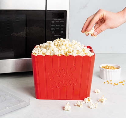Image of Nordic Ware Movie Night Popcorn Popper with popped popcorn next to microwave