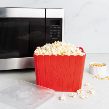 Nordic Ware Movie Night Popcorn Popper with translucent lid filled with popcorn in front of microwave