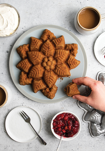 Image of baked spiced cake in new Nordic Ware Poinsettia cake Pan with hand taking a piece