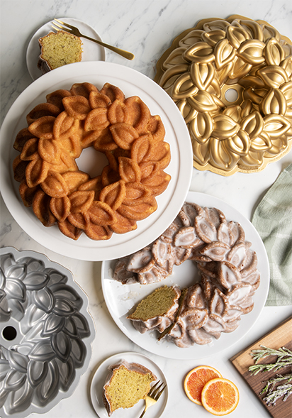 Image of two baked Laurel Wreath Bundt cakes with pans and ingredients in celebratory display. 
